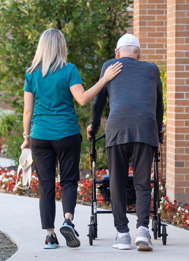 Therapist Walking With Senior Man with a Walker 