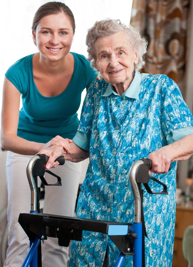 Home Health CNA standing next to senior woman with a walker