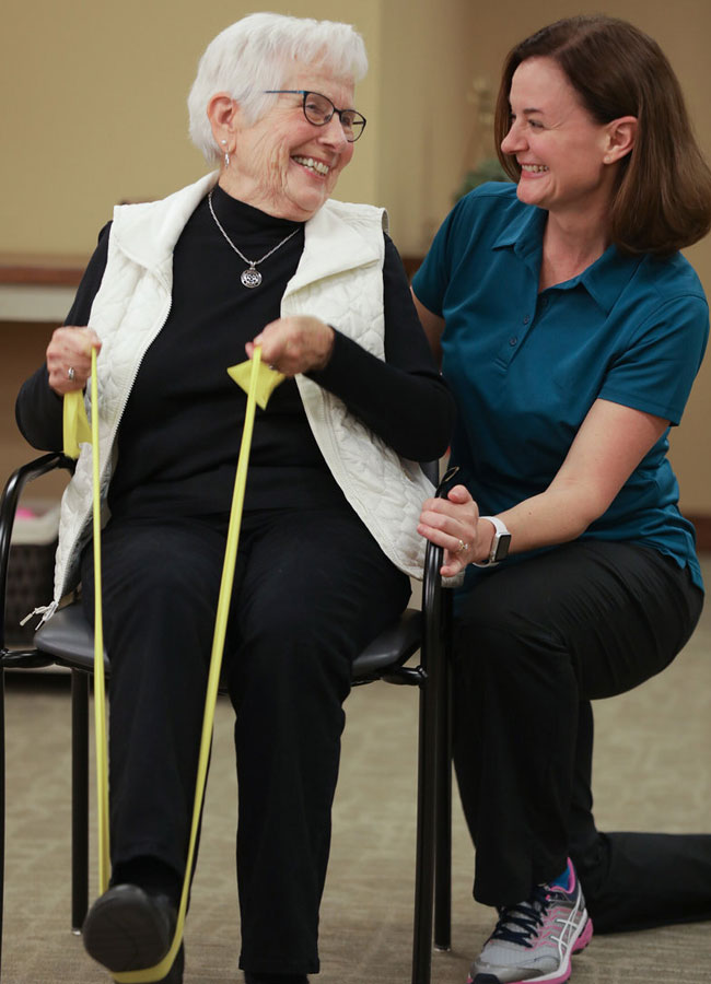 Physical Therapist smiling at elderly patient as she does her leg exercises